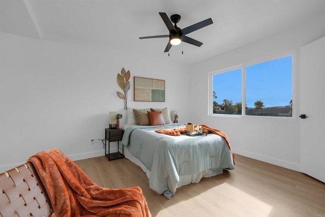 bedroom featuring baseboards, light wood-type flooring, and ceiling fan