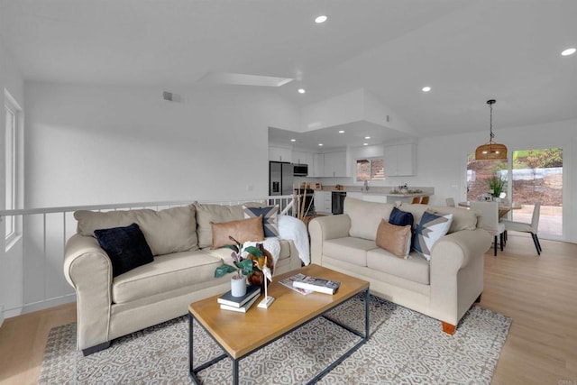 living room with recessed lighting, visible vents, light wood-style flooring, and vaulted ceiling