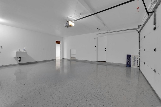 garage with a garage door opener, baseboards, and a sink