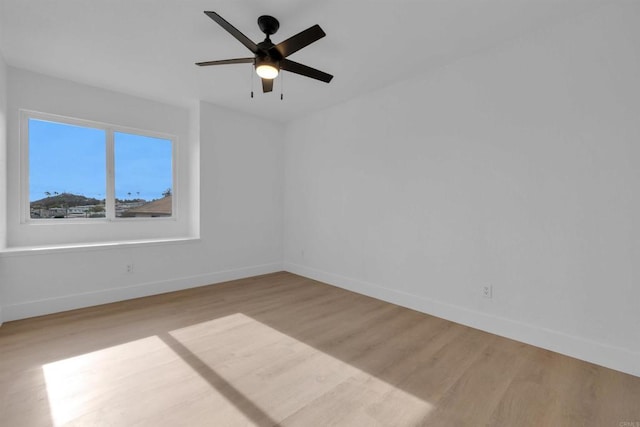 spare room with light wood finished floors, ceiling fan, and baseboards