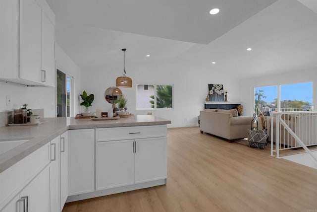 kitchen featuring white cabinets, a peninsula, light countertops, and light wood-type flooring