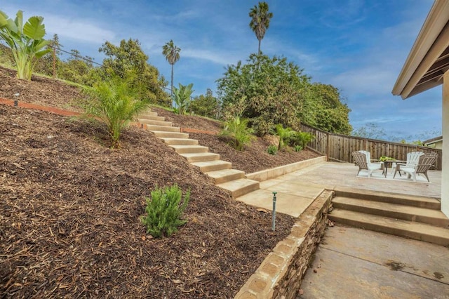 view of yard with a patio area, stairs, and fence