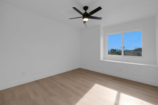 empty room with ceiling fan, baseboards, and wood finished floors