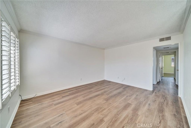 spare room with visible vents, light wood-style flooring, a textured ceiling, and crown molding