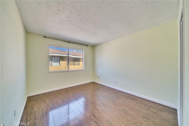 unfurnished room with a textured ceiling, baseboards, and wood finished floors