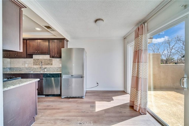 kitchen with light wood-type flooring, ornamental molding, backsplash, appliances with stainless steel finishes, and dark brown cabinets