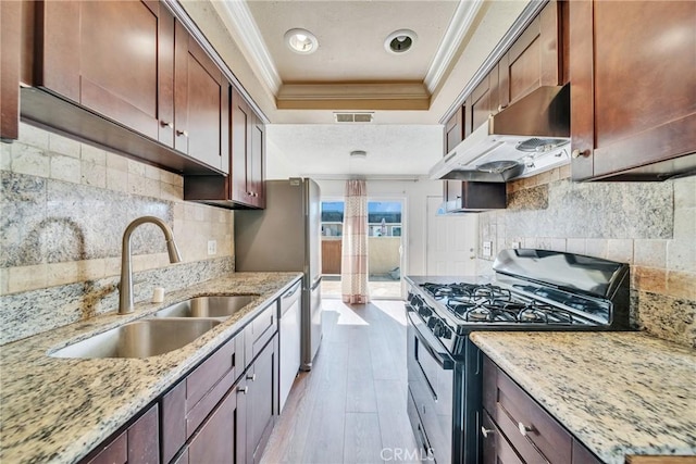 kitchen featuring gas stove, visible vents, a sink, under cabinet range hood, and a raised ceiling