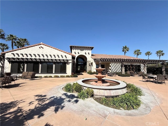 mediterranean / spanish home with a tiled roof, a patio area, and stucco siding