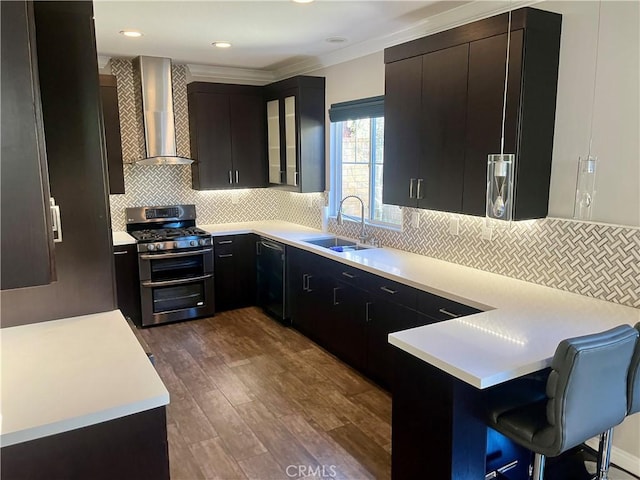 kitchen featuring a sink, double oven range, wall chimney range hood, dark wood-style floors, and light countertops