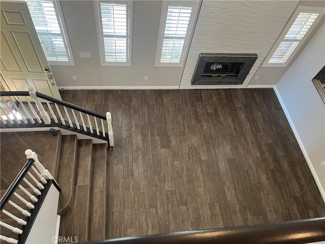 unfurnished living room featuring stairway, wood finished floors, and baseboards