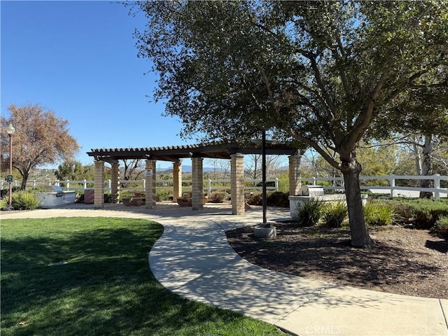 view of home's community with a pergola, a yard, and fence