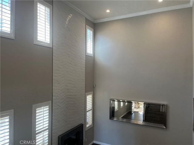 interior space with a glass covered fireplace, crown molding, and recessed lighting