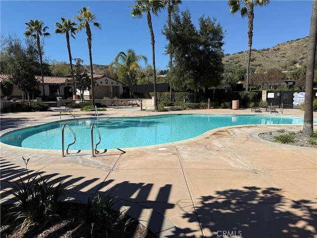 community pool with a patio and fence