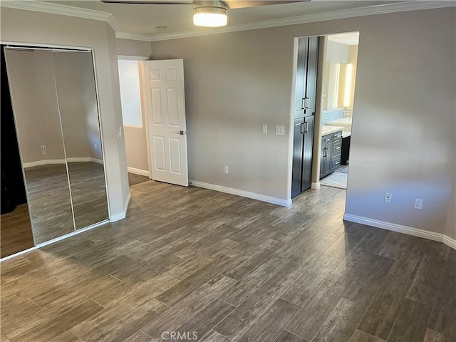 unfurnished bedroom with ornamental molding, baseboards, and dark wood-style flooring