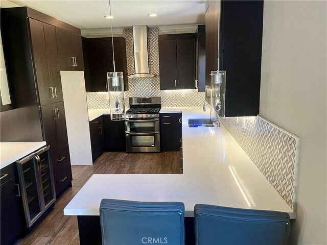 kitchen featuring a sink, double oven range, backsplash, wine cooler, and wall chimney range hood