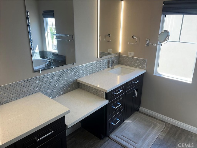 full bath with tasteful backsplash, vanity, baseboards, and wood finished floors