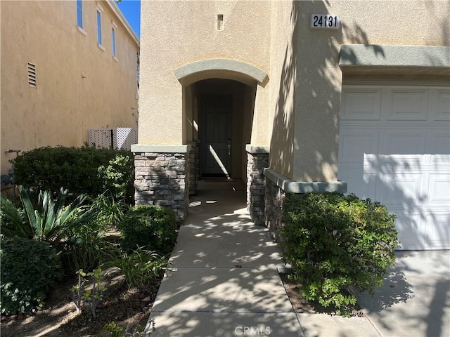 view of exterior entry with stucco siding and stone siding