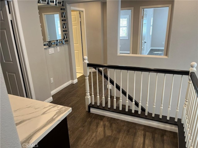 hallway featuring baseboards, an upstairs landing, and dark wood-type flooring