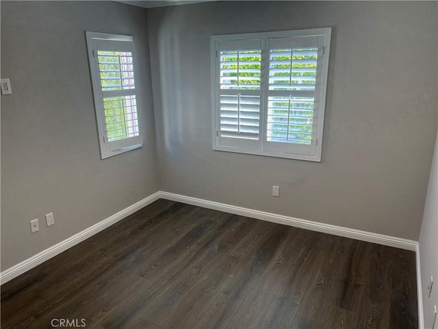 empty room featuring dark wood-type flooring and baseboards