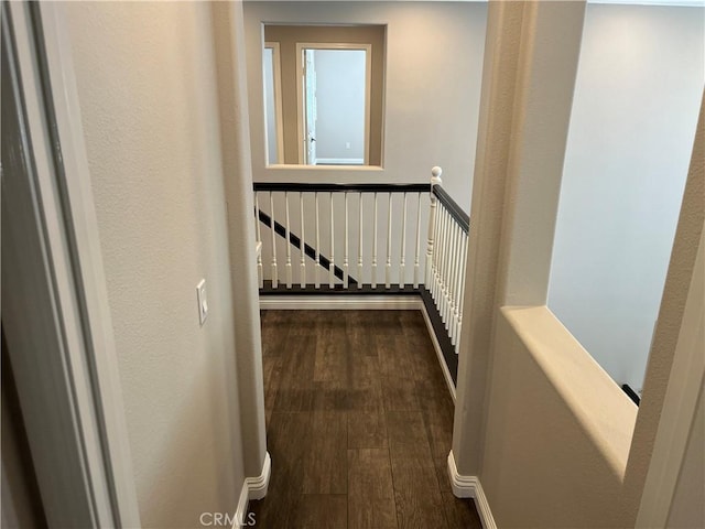 hallway with dark wood finished floors and an upstairs landing