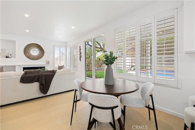 dining area featuring recessed lighting, a fireplace, light wood-type flooring, and baseboards