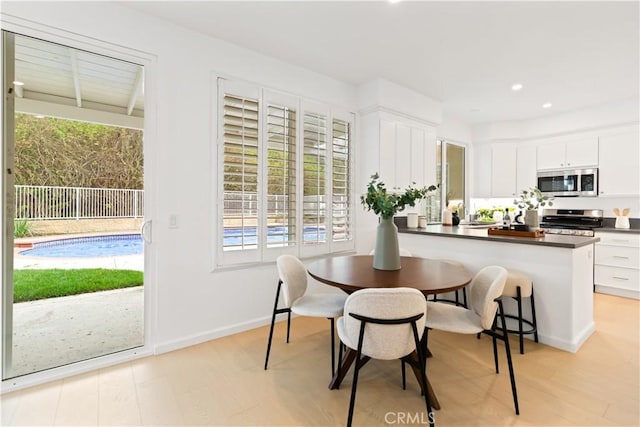 dining area with light wood-style flooring, recessed lighting, a healthy amount of sunlight, and baseboards