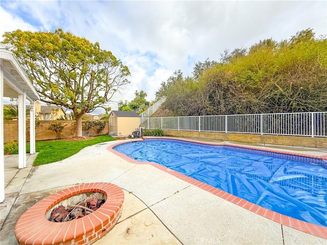 view of swimming pool featuring a fenced in pool, a shed, a fenced backyard, an outbuilding, and a patio