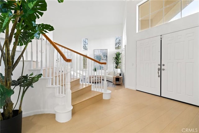 entrance foyer featuring stairway, baseboards, a high ceiling, and wood finished floors