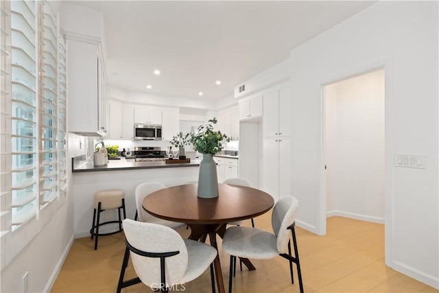 dining space featuring light wood-type flooring, recessed lighting, visible vents, and baseboards