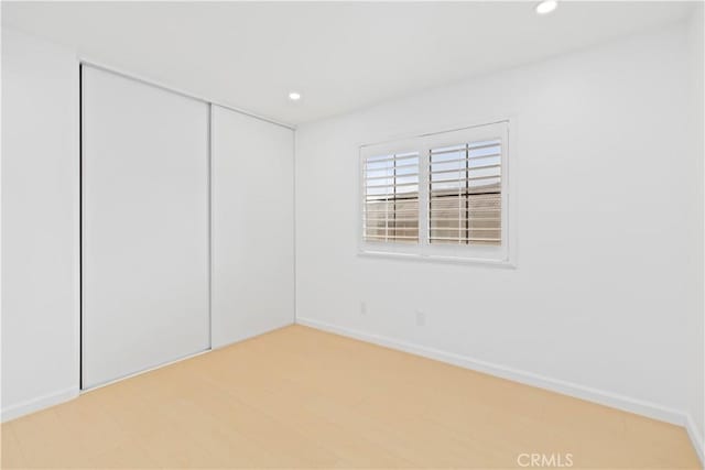 spare room featuring recessed lighting, light wood-type flooring, and baseboards