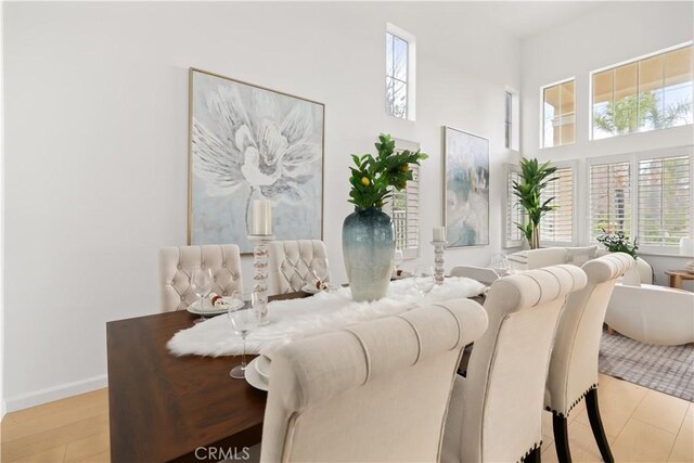 dining area featuring wood finished floors, baseboards, and a towering ceiling