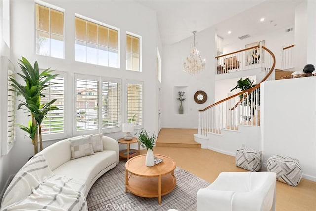 living area with stairs, visible vents, a towering ceiling, and a chandelier