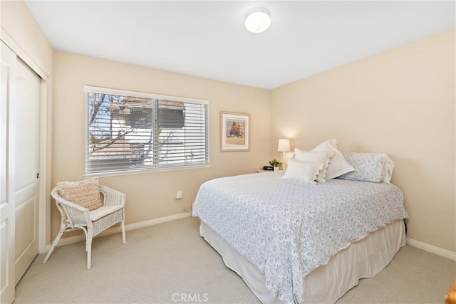 bedroom featuring a closet, light colored carpet, and baseboards