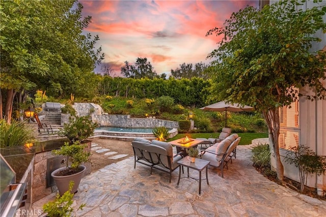 patio terrace at dusk with a fenced in pool and an outdoor fire pit