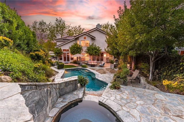 pool at dusk featuring an outdoor living space, an outdoor pool, and a patio