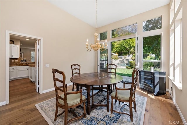 dining area with lofted ceiling, baseboards, wood-type flooring, and a chandelier