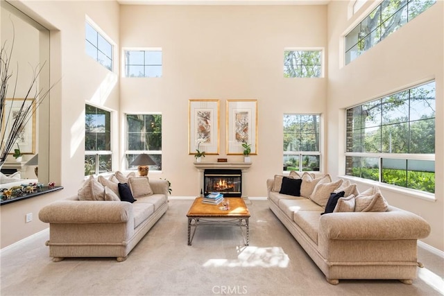 living area with a glass covered fireplace, carpet flooring, a healthy amount of sunlight, and baseboards