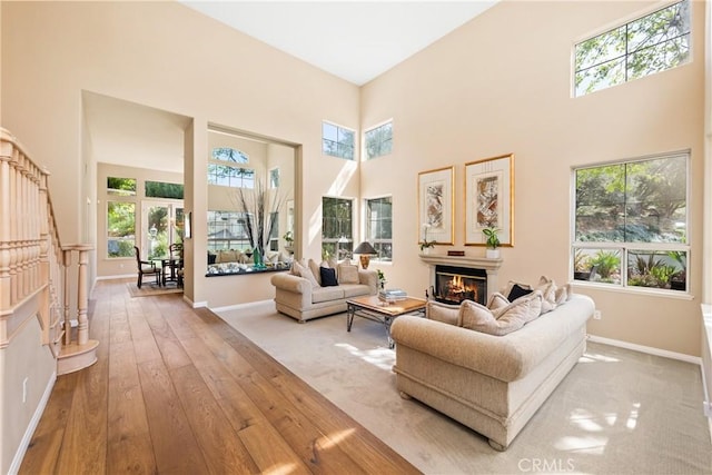 living room featuring baseboards, a high ceiling, and a glass covered fireplace