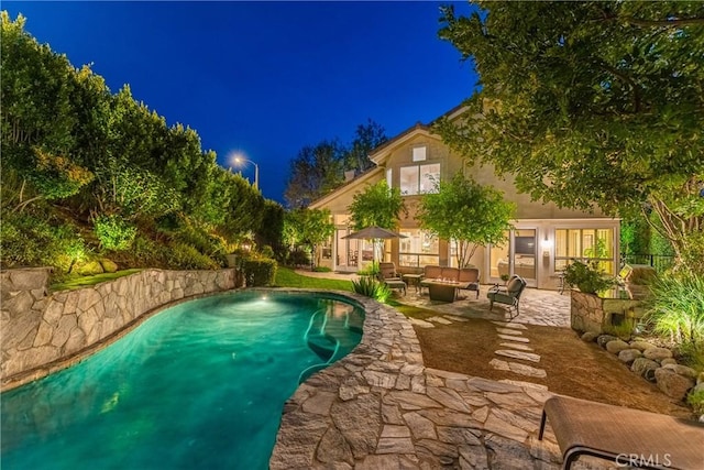 pool at twilight featuring a patio, an outdoor pool, and an outdoor hangout area