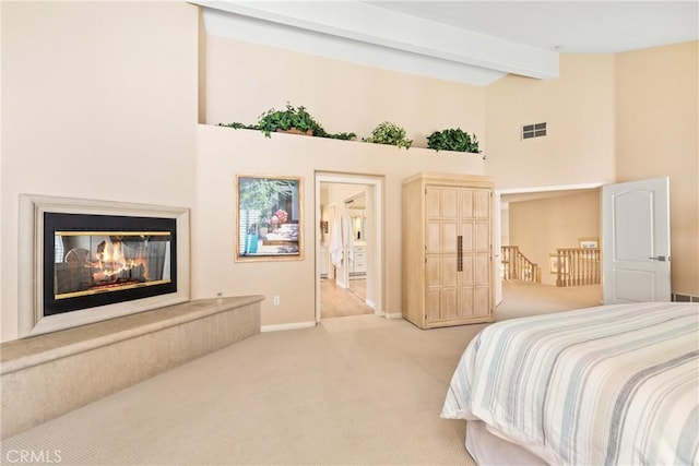 bedroom with visible vents, high vaulted ceiling, light carpet, a glass covered fireplace, and beamed ceiling