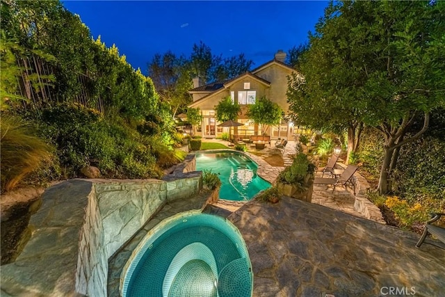 pool at twilight featuring an in ground hot tub, a patio area, and an outdoor pool