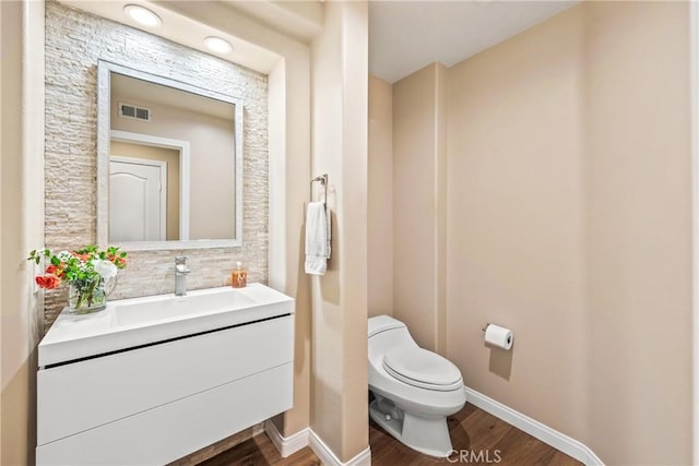 bathroom featuring vanity, wood finished floors, visible vents, baseboards, and toilet