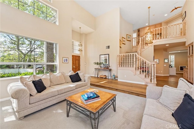 living room featuring stairway, baseboards, a high ceiling, and wood finished floors