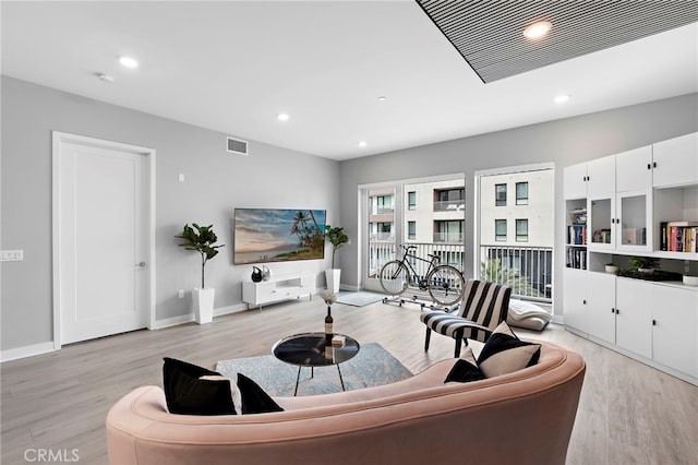 living room featuring light wood-type flooring, visible vents, and recessed lighting