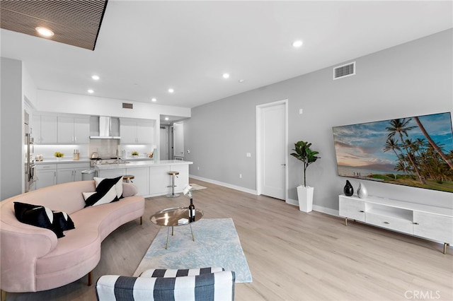 living area with light wood-style flooring, recessed lighting, visible vents, and baseboards