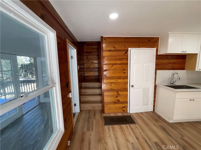 interior space with a sink, light wood-style floors, wood walls, and recessed lighting