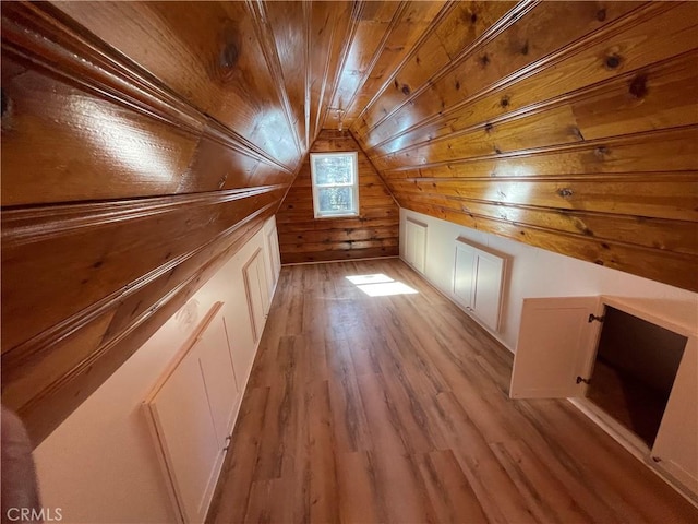 bonus room featuring wooden ceiling, wooden walls, light wood-style floors, and vaulted ceiling