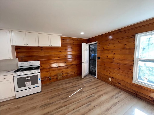 kitchen featuring white cabinetry, light wood finished floors, white gas range, and a wealth of natural light