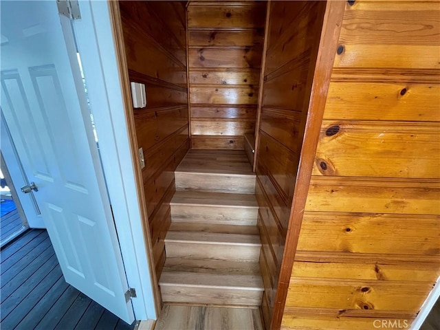 stairway featuring wooden walls and wood finished floors