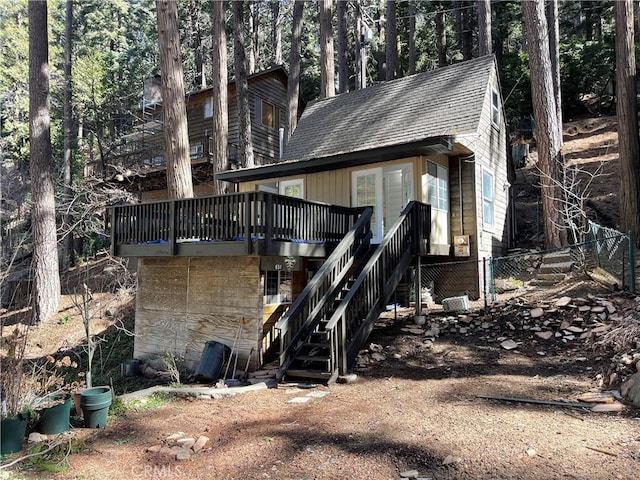 exterior space featuring a wooden deck, roof with shingles, and stairs